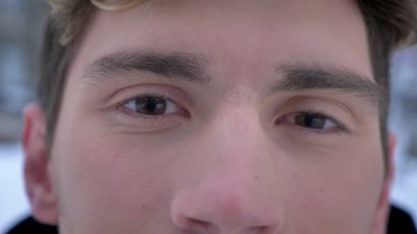Closeup střílet z mladých atraktivních kavkazské mužská tvář s hnědýma očima, s radostí při pohledu na fotoaparát