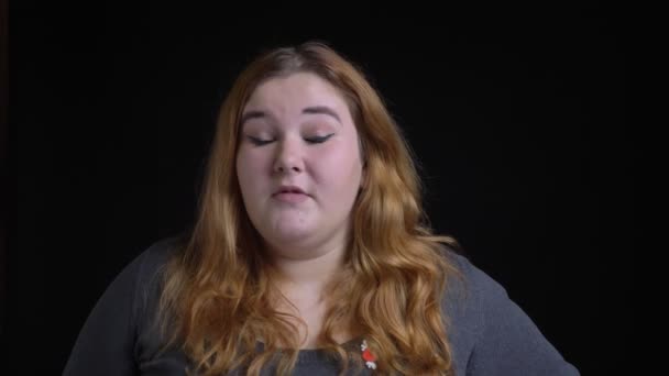 Крупним планом знімок молодої надмірної ваги кавказької жінки соромиться і чіпляється за голову рукою перед камерою — стокове відео