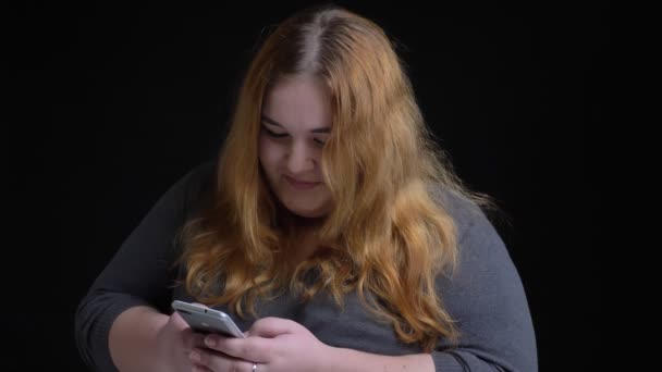 Vértes-lő a fiatal túlsúlyos kaukázusi nő a telefont, majd keres, a kamera, és mosolyogva — Stock videók