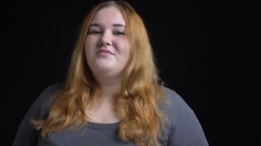 Kameraya bakarak ve seductively izole siyah arka plan ile gülümseyen genç kilolu beyaz kadın portre çekimleri