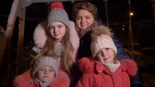 Ritratto di famiglia di madre caucasica e tre figlie che mangiano la neve e guardano felicemente in camera sullo sfondo della città serale . — Video Stock