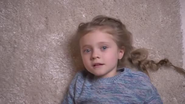 Topp skott porträtt av två små roliga tjejer pratar glatt med kameran att göra tricks och liggande på golvet. — Stockvideo