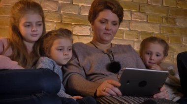 Beyaz anne ve kızları rahat ev ortamında kahkaha ile tablet içine izlerken aile portresi.