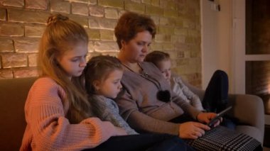 Yakın çekim aile portre profil beyaz anne ve kızları içine tablet rahat ev atmosferi büyük ilgi ile izlerken.