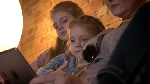 Yakın çekim portre iki küçük beyaz kız içine tablet rahat ev atmosferde dikkatle izliyor. — Stok video