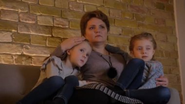 Beyaz anne iki korkmuş kızı sarılma ve rahat ev atmosferi korku filmi izlerken aile portresi.