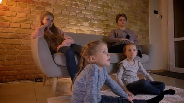 Portrait in profile of small caucasian girls watching movie attentively and talking with each other in cosy home atmosphere. — Stock Video