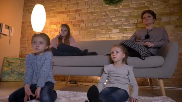 Familjeporträtt av kaukasiska mor med tre döttrar kommunicera och titta på film i mysiga hem atmosfär. — Stockvideo