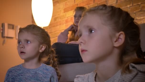 Gros plan portrait en profil de petites filles caucasiennes regardant le film attentivement et nerveusement dans une atmosphère confortable à la maison . — Video