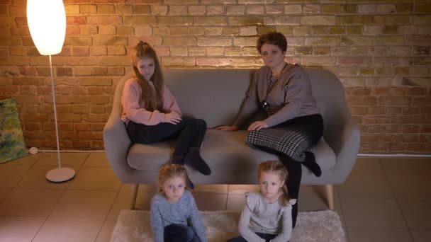 Nahoru shot kavkazské matka má tři dcery, sedí na gauči a sledovat film pozorně v příjemné domácí atmosféře.