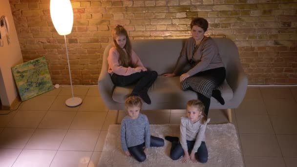 Plan du haut de la mère caucasienne avec trois filles assises sur le canapé et regardant un film dans une atmosphère confortable à la maison . — Video