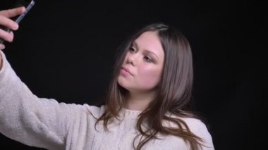 Genç oldukça beyaz kadın alarak selfies izole siyah arka plan ile telefonda portre çekimleri