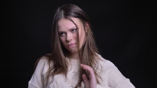 Genç çekici beyaz kadın saçlarını düzeltmesine ve kameraya bakarken gülümseyen utangaç closeup portresi — Stok video