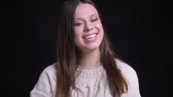 Nahaufnahme einer jungen attraktiven kaukasischen Frau, die fröhlich lacht und ihr brünettes Haar repariert und in die Kamera schaut — Stockvideo