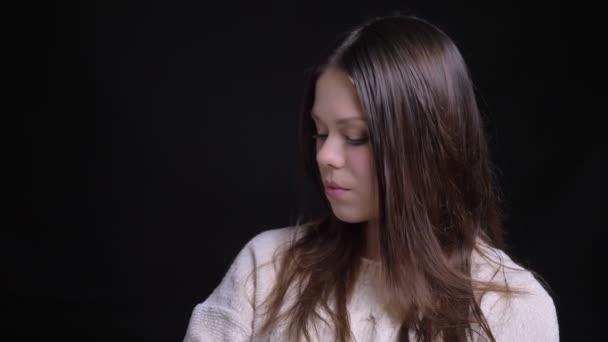 Closeup střílet z mladých atraktivních kavkazské bruneta žena obrací na kameru a uzavření tajemný pohled s izolované na černém pozadí — Stock video