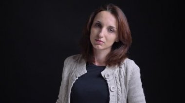 Sakin bir şekilde içine kamera siyah arka plan üzerine izlerken orta yaşlı esmer beyaz kadın portresi.