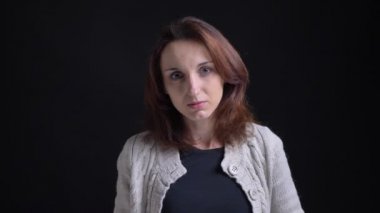 Orta yaşlı esmer beyaz kadın cidden içine kamera siyah arka plan üzerine izlerken portresi.