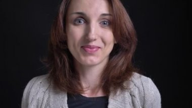 Alçakgönüllü içine kamera siyah arka plan üzerinde gülümseyen mutlu orta yaşlı esmer beyaz bir kadın portresi.