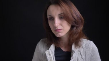 Orta yaşlı esmer beyaz kadın içine kamera siyah arka plan üzerine düşünceli izlerken portresi.
