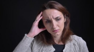 Siyah arka plan üzerine korkunç baş ağrısı olan orta yaşlı esmer beyaz kadın portresi.