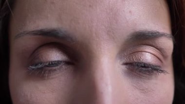 Yakın çekim göz-orta yaşlı esmer beyaz kadın cidden içine kamera siyah arka plan üzerine izlerken portresi.