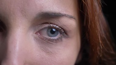 Yakın çekim yarı-portresi orta yaşlı esmer beyaz kadın cidden içine kamera siyah arka plan üzerine izlerken.