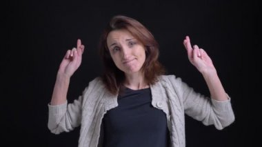 Orta yaşlı esmer beyaz kadın kamera içine umut siyah arka plan üzerine göstermek için parmak çarpı işareti işaretler el hareketi.