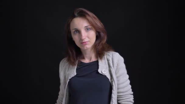 Porträt einer brünetten kaukasischen Frau mittleren Alters, die mit erhobenem Zeigefinger in die Kamera auf schwarzem Hintergrund zeigt. — Stockvideo