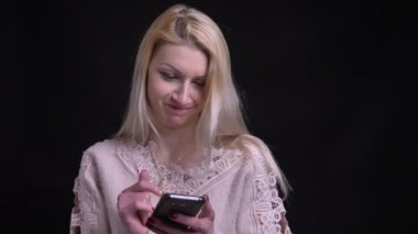 closeup ateş orta yaşlı beyaz sarışın kadın gülüyor ve kameraya bakarak telefon tarama