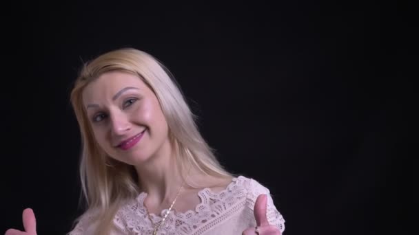 Съемка крупным планом белой женщины средних лет, показывающей большие пальцы вверх и улыбающейся, глядя прямо в камеру — стоковое видео