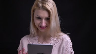Closeup ateş orta yaşlı beyaz kadın sonra kameraya bakıyor ve gülümsüyor tablet kullanma