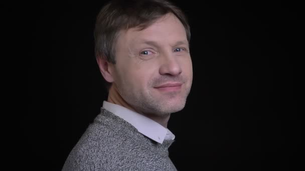 Closweup portrait of adult attractive caucasian male turning to camera and smiling cheerfully while looking forward — Stock Video