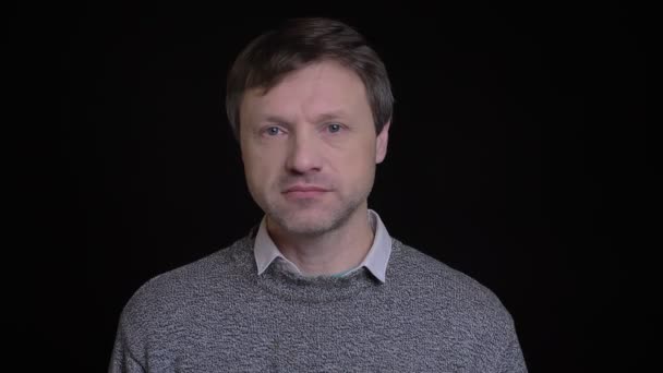 Nahaufnahme Porträt eines erwachsenen attraktiven kaukasischen Mannes, der mit emotionslosem Gesichtsausdruck direkt in die Kamera blickt — Stockvideo