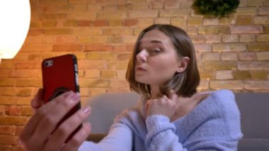 Telefonda selfies alarak ve kamera önünde poz genç beyaz sevimli kadın portresi portre