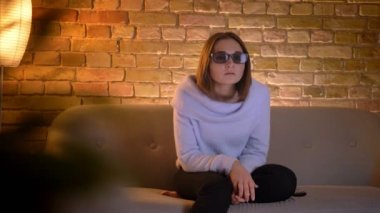 Şaşırtan bardaklarda Tv bir 3d aksiyon film izlerken genç oldukça beyaz kadın portre çekimleri ve kapalı kanepede oturan heyecanlı