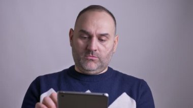 Orta portre çekimleri yaşlı beyaz adam tablet ardından kamera ve gülümseyen lookinga tarama.