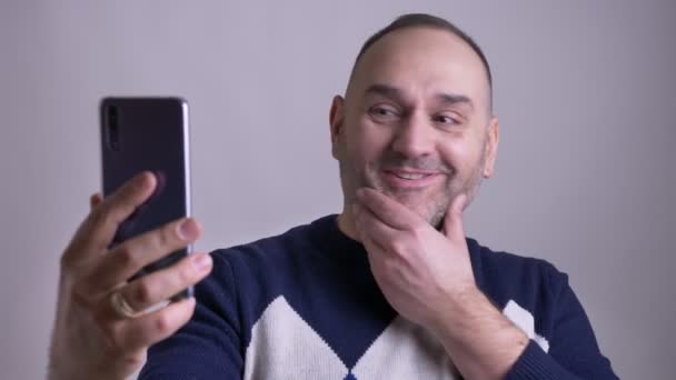 Closeup portret van volwassen Kaukasisch mannetje met een video callb praten en vrolijk lachend — Stockvideo