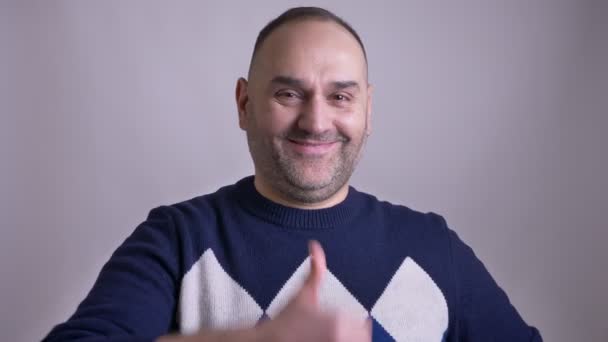 Primer plano retrato de hombre caucásico de mediana edad mostrando un pulgar hacia arriba y sonriendo y haciendo un ojo guiño mientras mira ta cámara — Vídeos de Stock