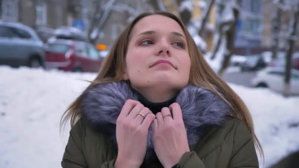 Closeup portrait of young pretty caucasian female with brunette hair being cold and warming her hands in a snowy day — Stock Video