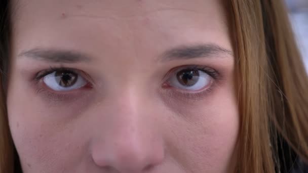 Closeup shoot of young pretty caucasian female face with brown eyes looking at camera in contemplation — Stock Video