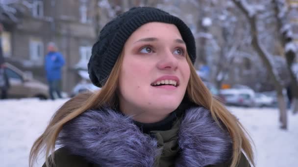 Gros plan pousse de jeune jolie femme caucasienne aux cheveux bruns étant heureux et regardant autour d'elle avec excitation dans une journée d'hiver enneigée en plein air — Video