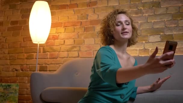 Close-up portret van gember curly-haired Kaukasische meisje praten in videochat graag op gezellige huis achtergrond. — Stockvideo