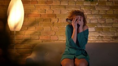 Korku filmi izlemek ve yüzü ile gizleme korkmuş zencefil kıvırcık saçlı beyaz kız portre rahat ev arka plan üzerinde eller.