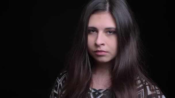Nahaufnahme Shooting der jungen charmanten schwarzhaarigen Kaukasierin, die direkt in die Kamera mit isoliertem Hintergrund blickt — Stockvideo