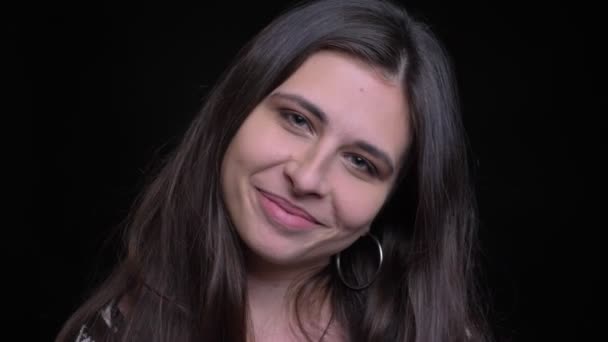 Zbliżenie strzelać z młodych wspaniały kaukaski kobieta uśmiecha się radośnie i patrząc na kamery z tła na czarnym tle — Wideo stockowe