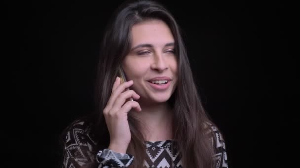 Closeup σουτ του νεαρή γοητευτική καυκάσιος γυναίκα έχοντας μια ευτυχισμένη συνομιλία στο τηλέφωνο χαμογελαστός και γελά, μπροστά από την κάμερα — Αρχείο Βίντεο