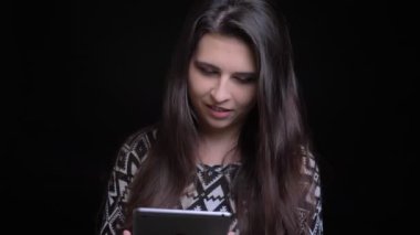 Portre çekimleri genç çekici beyaz kadın gülümseyerek ve arka plan üzerinde siyah izole kameraya bakarak konuşmaya tablet kullanma