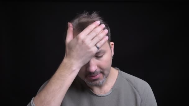 Портрет белого мужчины средних лет с сережкой, жестикулирующий знак лица, чтобы показать раздражение в камеру на черном фоне . — стоковое видео