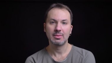 Portresi orta yaşlı beyaz adam küpe onaylayarak içine kamera siyah arka plan üzerine başını sallayarak ile konsantre.