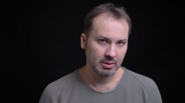 Ne yazık ki içine kamera siyah arka plan üzerine izlerken Küpeli umutsuz orta yaşlı beyaz adamın portresi.